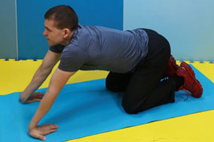 マットの上で手の平を床につけ、ストレッチする男性(ヘイキさん)