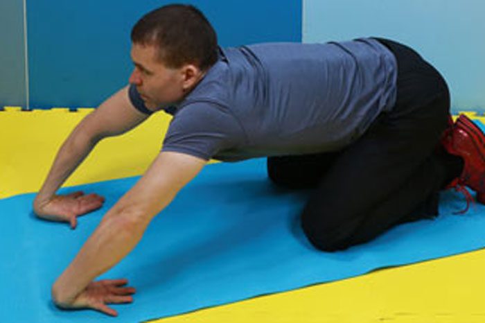 マットの上で手の甲を床につけ、リバースリストストレッチする男性(ヘイキさん)
